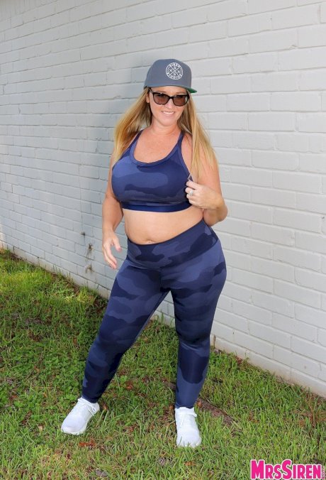 Short cougar Dee Siren posing in her sexy leggings and top in the garden