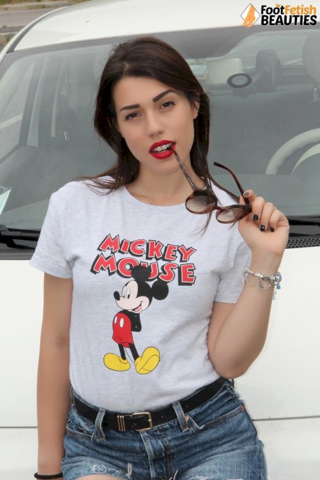 Hot girl displays her sexy feet in a car while wearing a Mickey Mouse T-shirt