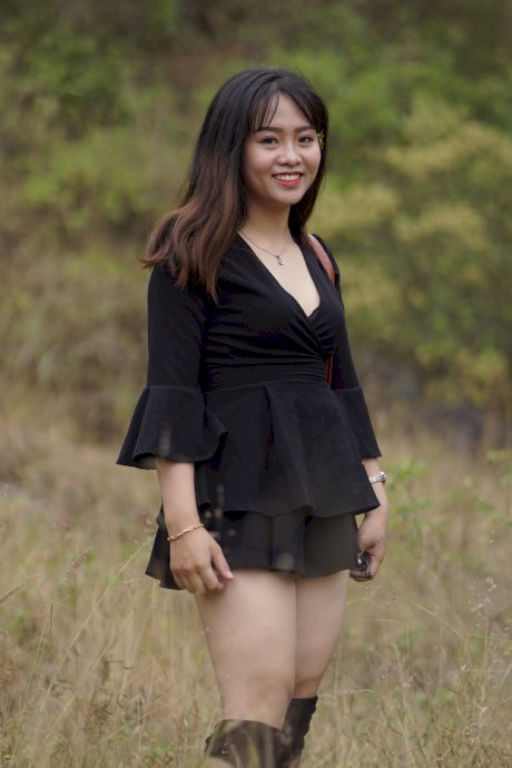 Gorgeous Asian babe posing in her black dress and boots in nature