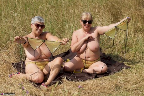 Old lesbians catch rays on their large breasts while sunbathing in a field