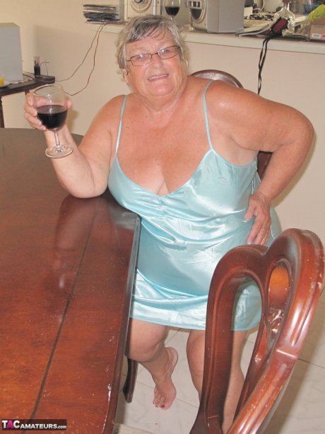 Old British fatty Grandma Libby sticks in a wine bottle in her cunt on a table
