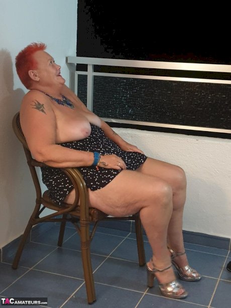 Fat nan with short red hair presses her big boobs and butt up against glass