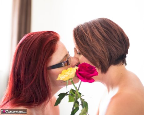 Middle-aged lesbians share a tender kiss while holding flowers