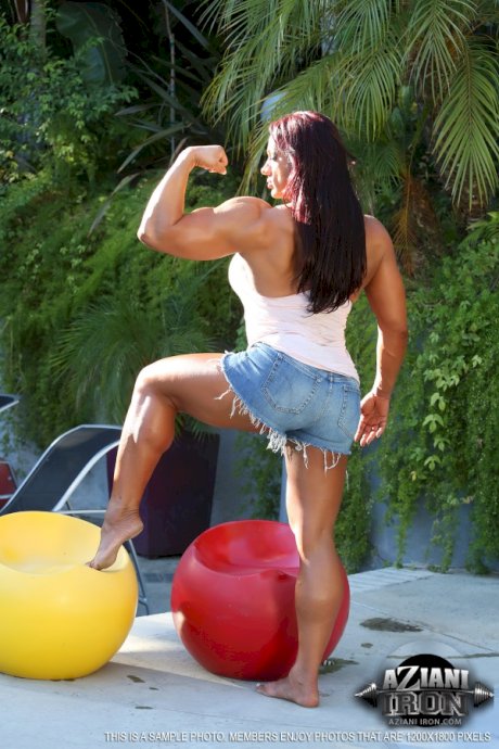 Female bodybuilder Amber Deluca cups a boob while showing her muscled body