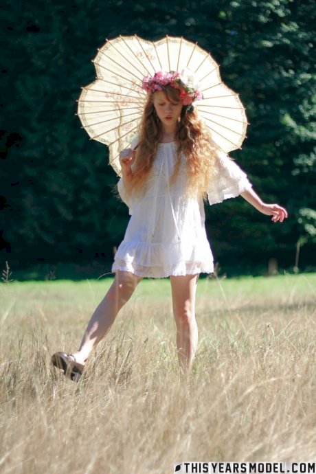 Charming redheaded teen Dolly Little holds a parasol while getting naked porn pics
