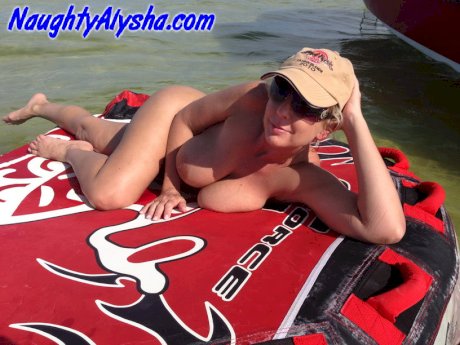 Big titted amateur lounges on an air mattress while naked in a ball cap