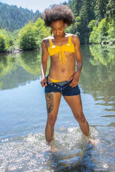 Afro-American babe Nikki Darling exposes her hairy inked body in the river