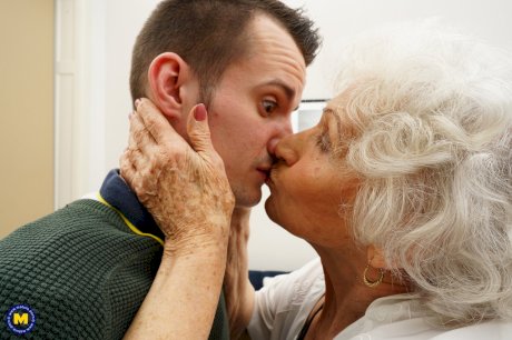 Old woman kisses a young man while seducing him for a badly needed fuck