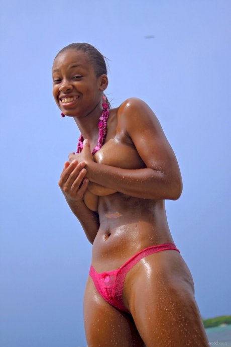 Ebony girl Tierra exposes her big natural tits while stripping in the sea