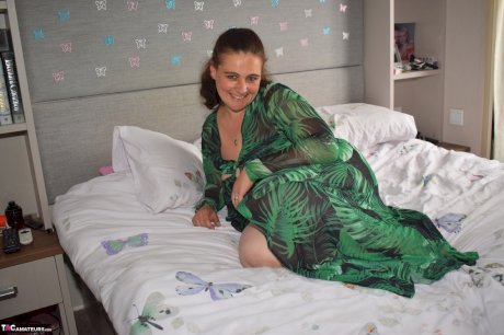 Fat woman exposes herself on a bed while wearing a long dress