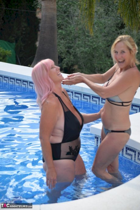 Mature BBW Melody and her girlfriend walk hand in hand by a pool in swimwear