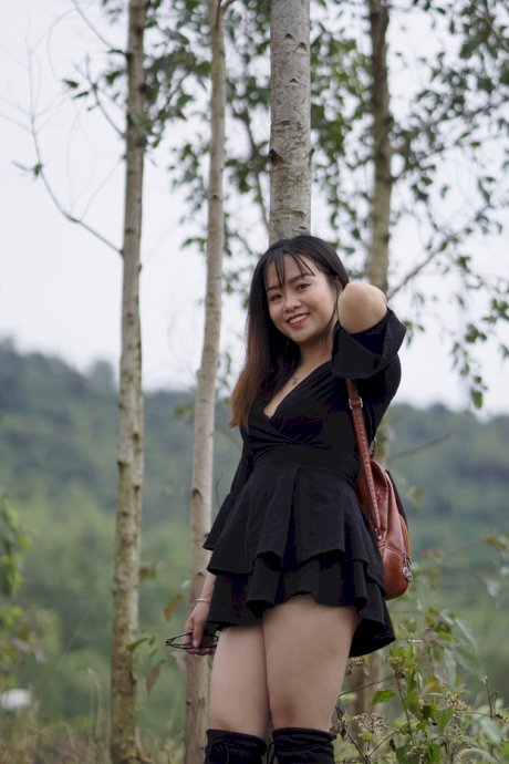 Gorgeous Asian babe posing in her black dress and boots in nature